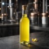 Bottiglia bordolese in vetro trasparente da 375 ml con tappo, piena di limoncello, ambientazione laboratorio artigianale